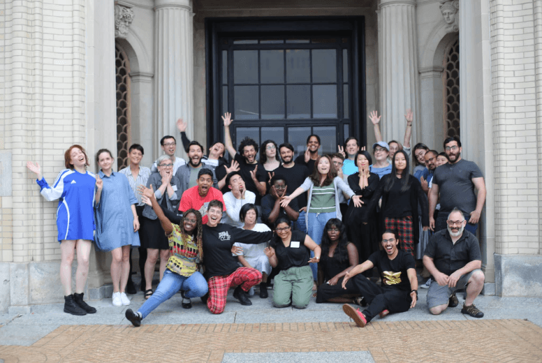 Group photo of participants smiling enthusiastically with their hands in the air.